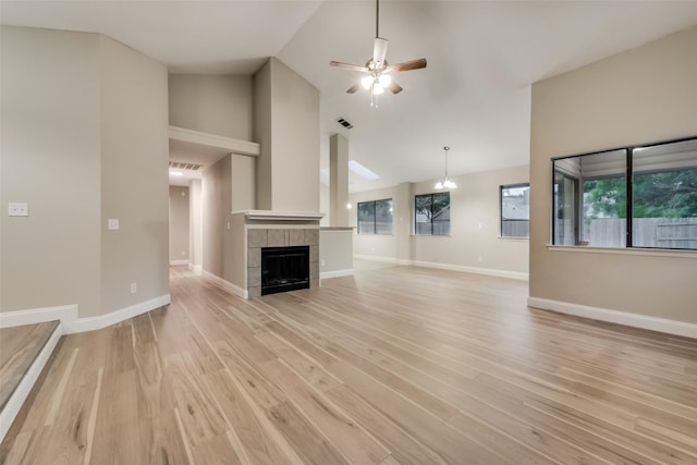 3301 Cliffview Dr, Corinth, TX 76210 - unfurnished living room featuring ceiling fan, light wood-style flooring, high vaulted ceiling, baseboards, and a tiled fireplace