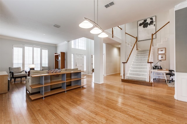 3704 Roxbury Ln, Plano, TX 75025 - living room featuring stairs, light wood-type flooring, crown molding, and a towering ceiling