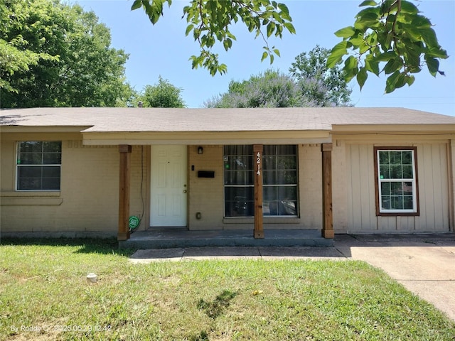 4214 Mehalia Dr, Dallas, TX 75241 - doorway to property with a lawn, brick siding, board and batten siding, and a shingled roof