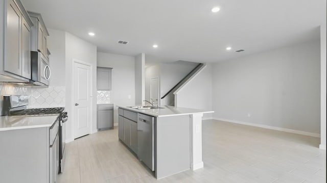 804 Sage Dr, Boyd, TX 76234 - kitchen with stainless steel appliances, gray cabinetry, a sink, backsplash, and an island with sink