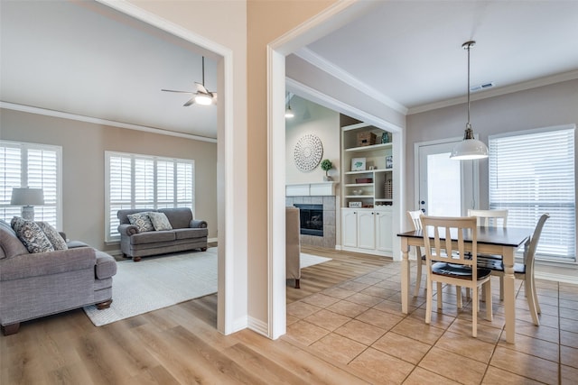 1908 Thompson Ct, Flower Mound, TX 75028 - dining room featuring ornamental molding, healthy amount of natural light, a ceiling fan, a tile fireplace, and built in shelves