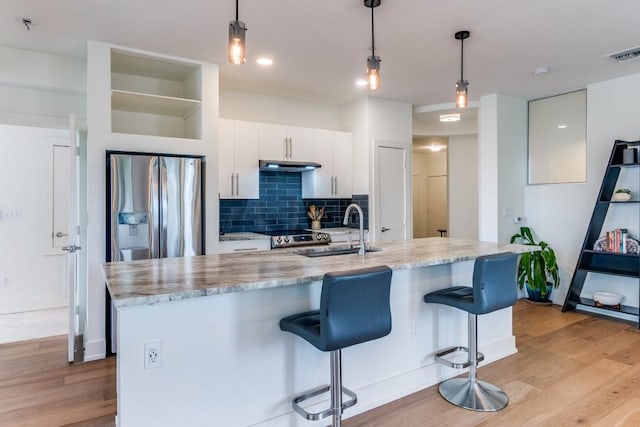4333 Gilbert Ave Unit 329, Dallas, TX 75219 - kitchen with stainless steel fridge, under cabinet range hood, light wood-style flooring, a sink, and tasteful backsplash