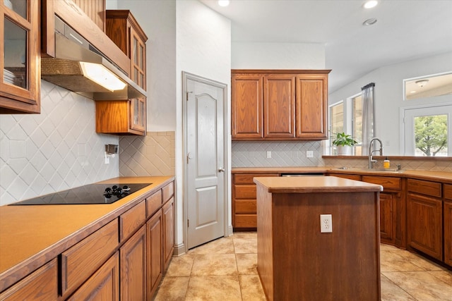 1801 Highland Springs Dr, Haslet, TX 76052 - kitchen featuring under cabinet range hood, a sink, black electric cooktop, backsplash, and brown cabinets