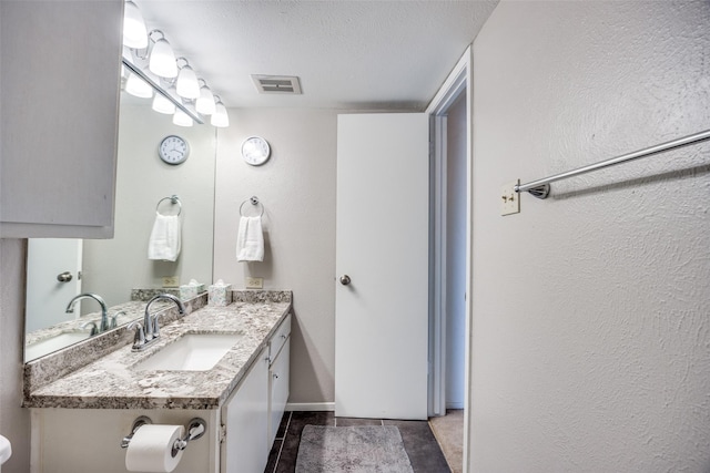 12834 Midway Rd Unit 1105, Dallas, TX 75244 - bathroom featuring vanity, tile patterned flooring, a textured wall, a textured ceiling, and baseboards