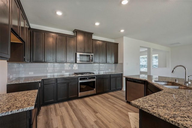 4224 Wood River Trl, Prosper, TX 75078 - kitchen featuring appliances with stainless steel finishes, a sink, light stone counters, light wood finished floors, and dark brown cabinets