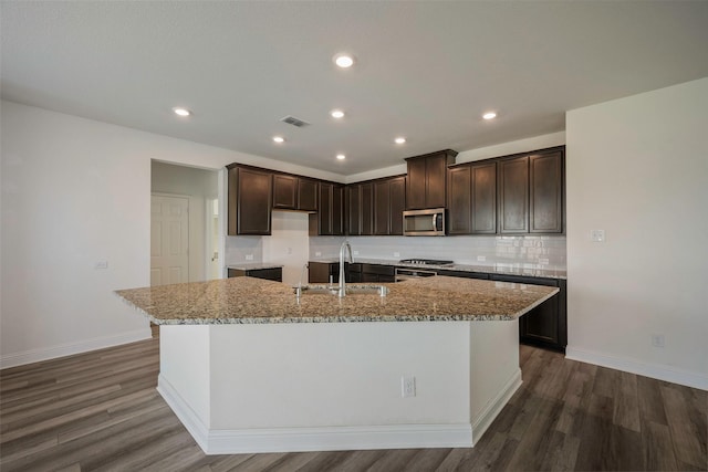 4224 Wood River Trl, Prosper, TX 75078 - kitchen with stainless steel microwave, a sink, dark brown cabinets, dark wood-type flooring, and a center island with sink