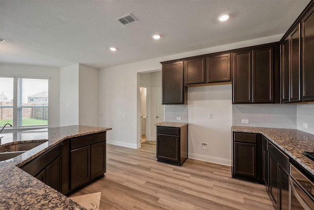 4224 Wood River Trl, Prosper, TX 75078 - kitchen featuring a sink, dark stone counters, dark brown cabinets, light wood finished floors, and backsplash