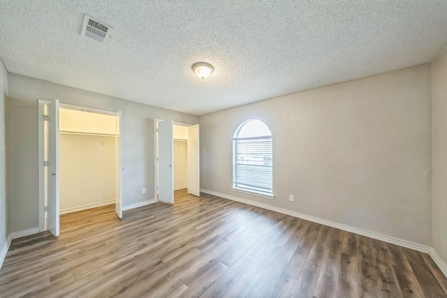 715 San Juan Dr, Duncanville, TX 75116 - unfurnished bedroom with wood finished floors, baseboards, a textured ceiling, and a walk in closet