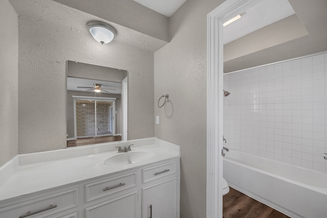715 San Juan Dr, Duncanville, TX 75116 - bathroom featuring a textured wall, vanity, wood finished floors, ceiling fan, and shower / washtub combination