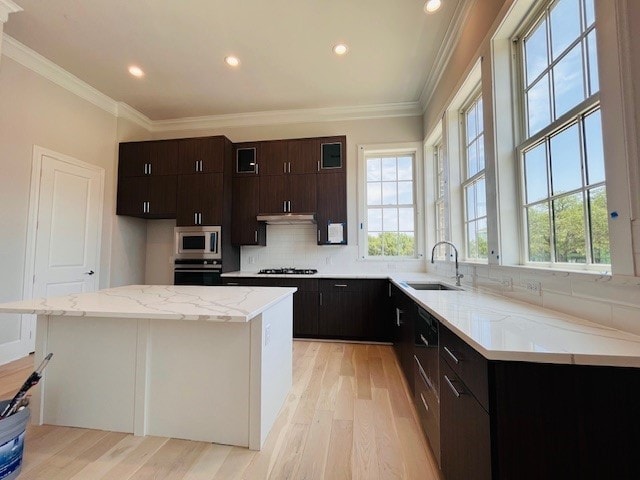 5024 Magnolia Cir, Addison, TX 75001 - kitchen featuring oven, light wood-style flooring, tasteful backsplash, crown molding, and a center island
