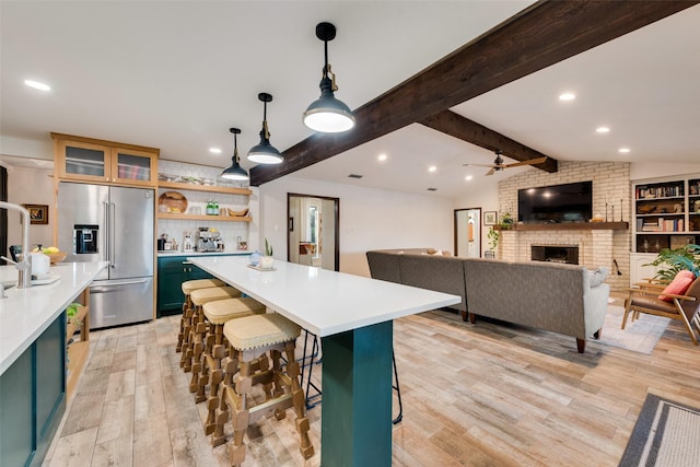 8608 Funtier Ct, Fort Worth, TX 76179 - kitchen with high end refrigerator, light wood-type flooring, light countertops, a center island, and a brick fireplace