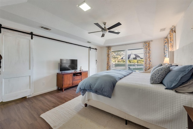 8608 Funtier Ct, Fort Worth, TX 76179 - bedroom with a barn door, a tray ceiling, wood finished floors, baseboards, and a ceiling fan