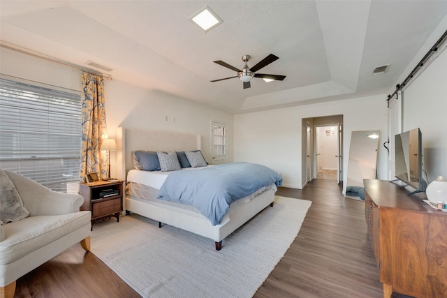 8608 Funtier Ct, Fort Worth, TX 76179 - bedroom with a barn door, a raised ceiling, wood finished floors, baseboards, and ceiling fan