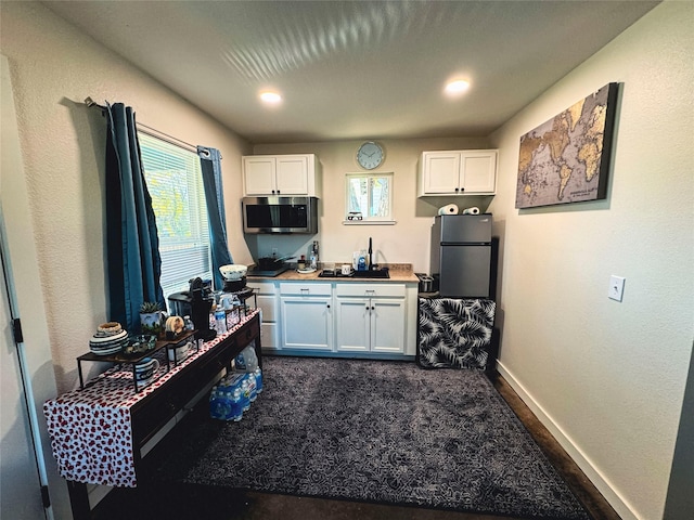 1000 S 4th St, Bonham, TX 75418 - kitchen featuring stainless steel appliances, white cabinets, baseboards, and dark carpet