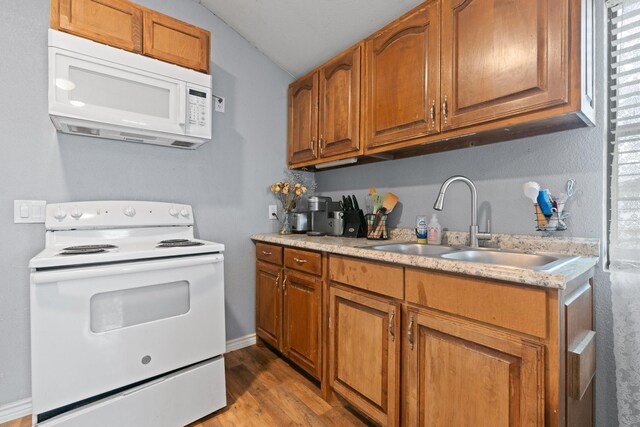 2600 Dave Angel Rd, Burleson, TX 76028 - kitchen with white appliances, vaulted ceiling, brown cabinetry, and light countertops