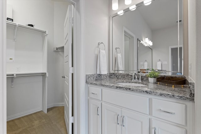 2451 S Gate Dr, Richardson, TX 75080 - bathroom featuring vanity, a walk in closet, and baseboards