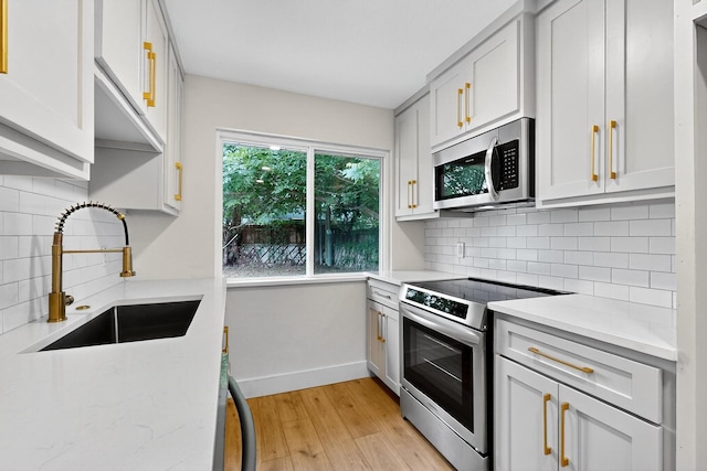 909 Dover Cir, Gainesville, TX 76240 - kitchen featuring appliances with stainless steel finishes, a sink, light wood-style floors, baseboards, and tasteful backsplash