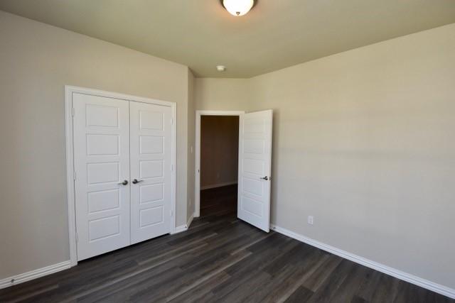 2408 Donella Dr, Denton, TX 76207 - unfurnished bedroom featuring dark wood-type flooring, baseboards, and a closet