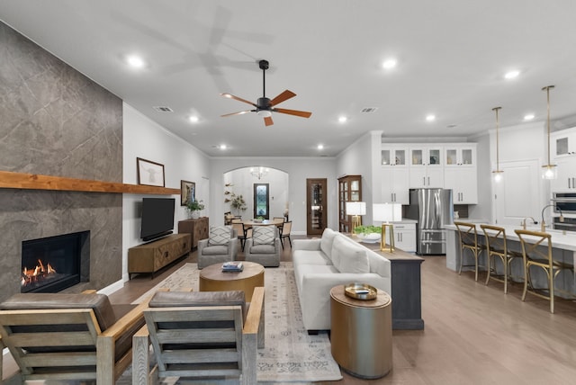 7800 Kentmere, The Colony, TX 75056 - living room with arched walkways, ceiling fan, a tile fireplace, recessed lighting, and light wood-type flooring