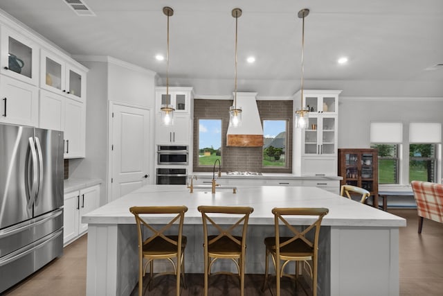 7800 Kentmere, The Colony, TX 75056 - kitchen with appliances with stainless steel finishes, a sink, premium range hood, crown molding, and an island with sink