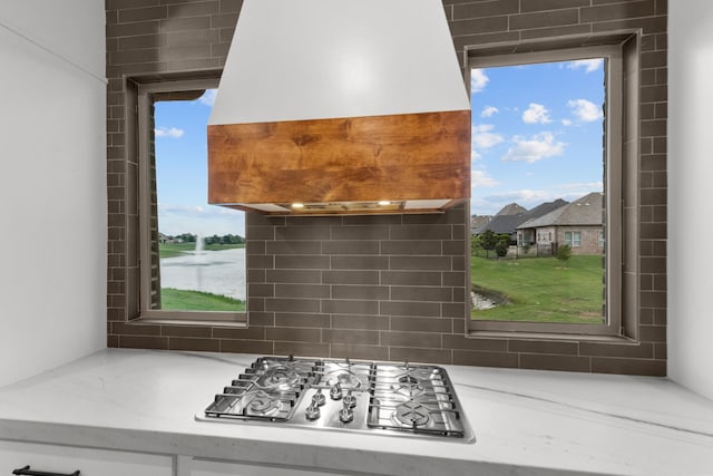 7800 Kentmere, The Colony, TX 75056 - kitchen with stainless steel gas cooktop, ventilation hood, healthy amount of natural light, and light stone counters
