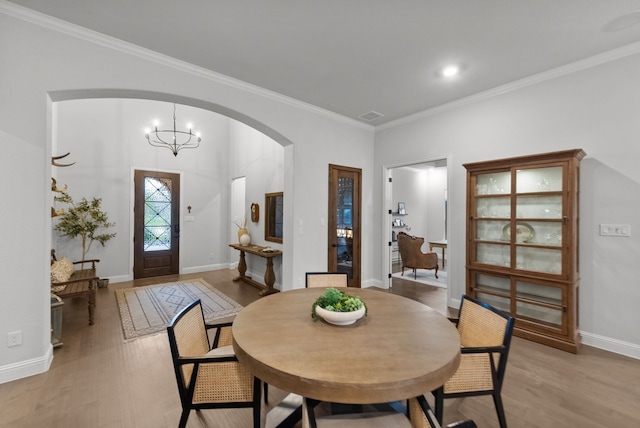 7800 Kentmere, The Colony, TX 75056 - dining area with arched walkways, light wood finished floors, ornamental molding, baseboards, and a chandelier
