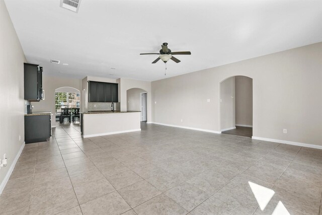 714 Shady Meadow Ln, Glenn Heights, TX 75154 - unfurnished living room featuring arched walkways, ceiling fan, light tile patterned floors, and baseboards