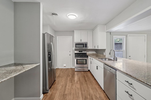 3620 W Biddison St, Fort Worth, TX 76109 - kitchen featuring stainless steel appliances, a sink, wood finished floors, and white cabinets