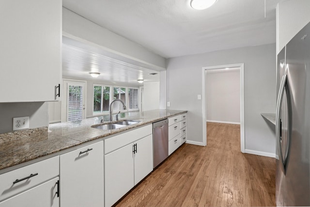 3620 W Biddison St, Fort Worth, TX 76109 - kitchen with stainless steel appliances, a sink, wood finished floors, white cabinets, and light stone counters