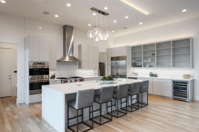 6420 Azalea Ln, Dallas, TX 75230 - kitchen featuring appliances with stainless steel finishes, wall chimney range hood, beverage cooler, a breakfast bar, and tasteful backsplash