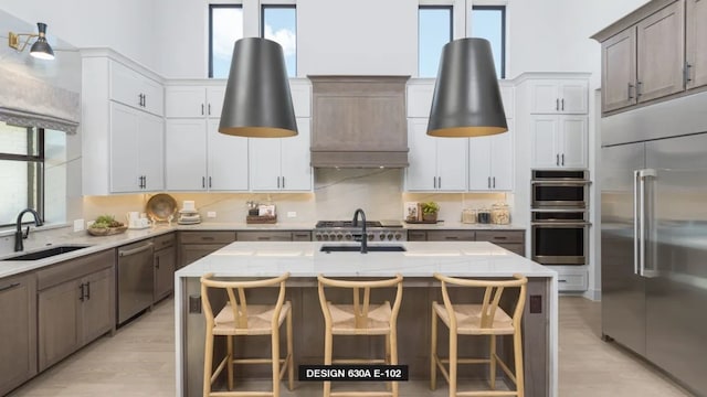 712 Bear Creek Dr, Hurst, TX 76054 - kitchen featuring appliances with stainless steel finishes, a sink, plenty of natural light, light wood-style floors, and a towering ceiling