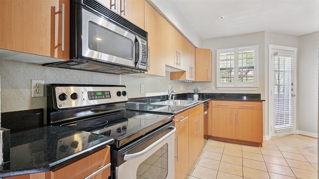 3901 Travis St Unit 230, Dallas, TX 75204 - kitchen featuring stainless steel appliances, a sink, light tile patterned floors, and dark stone counters