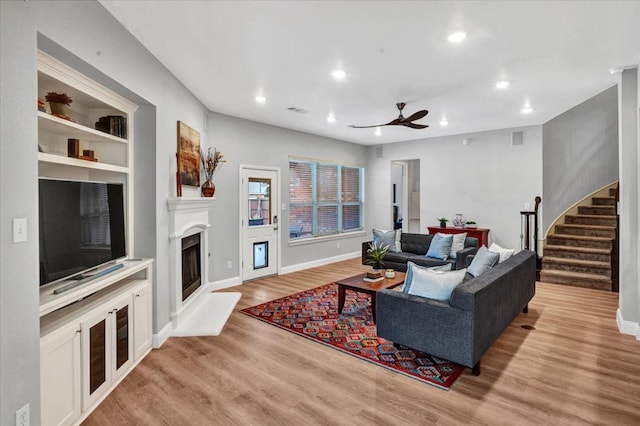 1516 Stonehill Ct, Allen, TX 75002 - living area featuring wood finished floors, a fireplace with raised hearth, a ceiling fan, stairway, and recessed lighting