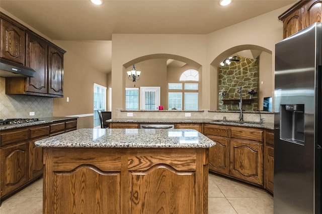1518 E Oates Rd, Garland, TX 75043 - kitchen with appliances with stainless steel finishes, under cabinet range hood, tasteful backsplash, a center island, and light stone countertops