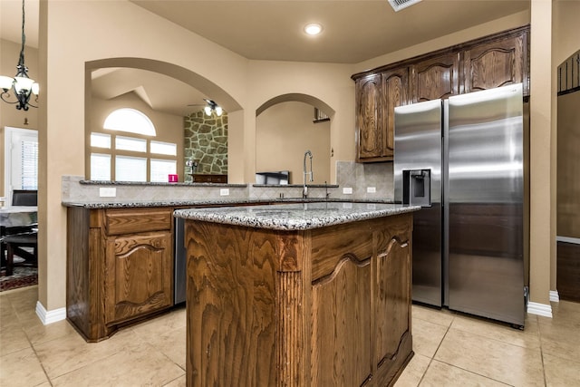 1518 E Oates Rd, Garland, TX 75043 - kitchen featuring stainless steel fridge with ice dispenser, a kitchen island, arched walkways, tasteful backsplash, and light tile patterned flooring