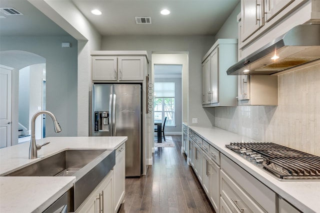 1031 Devonshire Dr, Allen, TX 75013 - kitchen with appliances with stainless steel finishes, a sink, under cabinet range hood, dark wood-style floors, and arched walkways