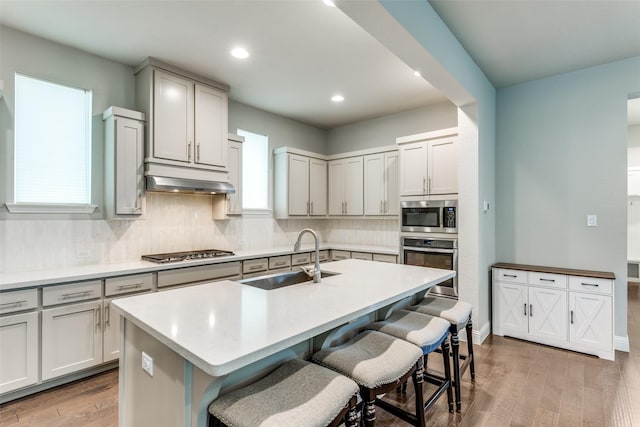 1031 Devonshire Dr, Allen, TX 75013 - kitchen with appliances with stainless steel finishes, a sink, light wood-type flooring, tasteful backsplash, and a breakfast bar