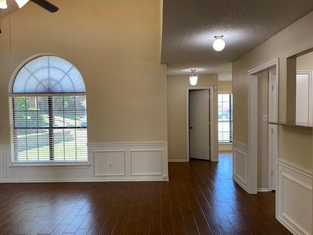 1404 Ranchview Ct, Carrollton, TX 75007 - unfurnished room with wainscoting, a textured ceiling, dark wood finished floors, a decorative wall, and ceiling fan