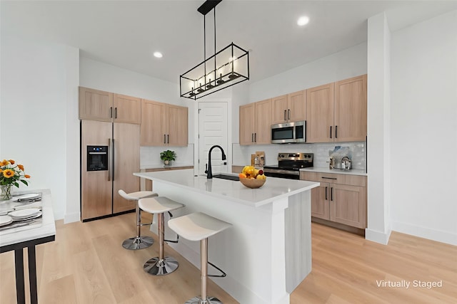 8901 Lowell St, Rowlett, TX 75089 - kitchen featuring appliances with stainless steel finishes, light brown cabinets, a kitchen bar, light wood-style floors, and light countertops