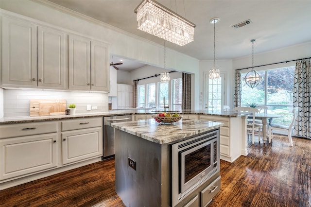2841 Winding Creek Rd, Prosper, TX 75078 - kitchen with a chandelier, stainless steel appliances, a peninsula, dark wood-style floors, and tasteful backsplash