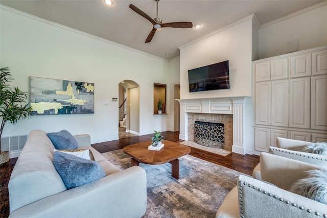 2841 Winding Creek Rd, Prosper, TX 75078 - living room with arched walkways, ceiling fan, dark wood-style floors, ornamental molding, and a tile fireplace