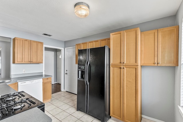 2969 Eric Ln, Farmers Branch, TX 75234 - kitchen with black refrigerator with ice dispenser, white dishwasher, range, light brown cabinetry, and light tile patterned floors