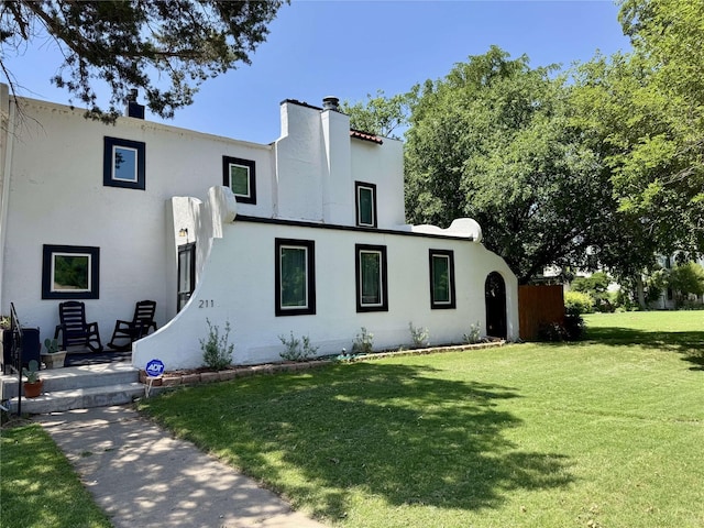 211 NW Alpine Dr, Plainview, TX 79072 - view of front of house featuring a front lawn, stucco siding, and a chimney