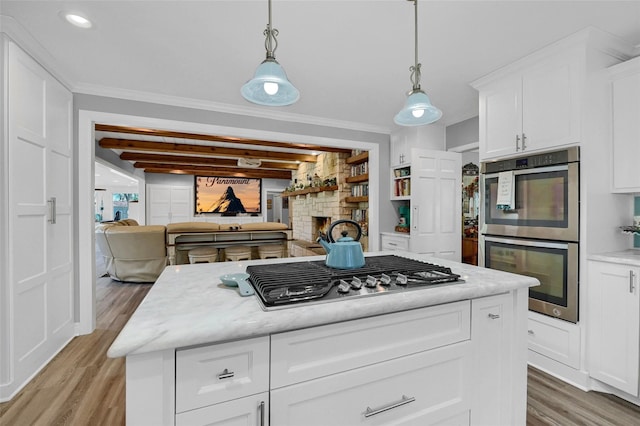 1016 Crestview Dr, Sherman, TX 75092 - kitchen with stainless steel appliances, light wood-style floors, a fireplace, white cabinetry, and decorative light fixtures