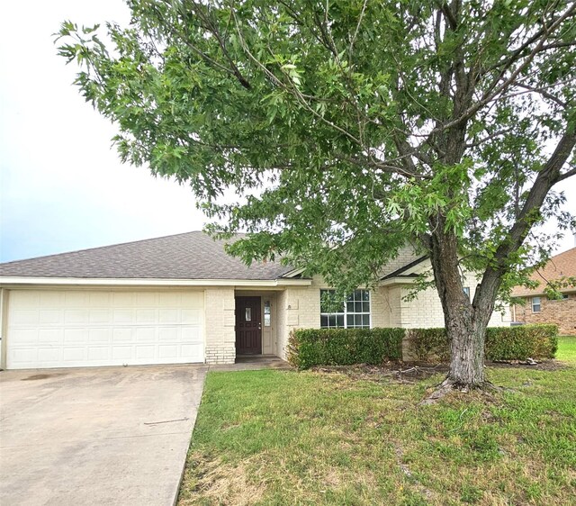21 Circle Dr, Whitney, TX 76692 - ranch-style house featuring an attached garage, concrete driveway, brick siding, roof with shingles, and a front lawn