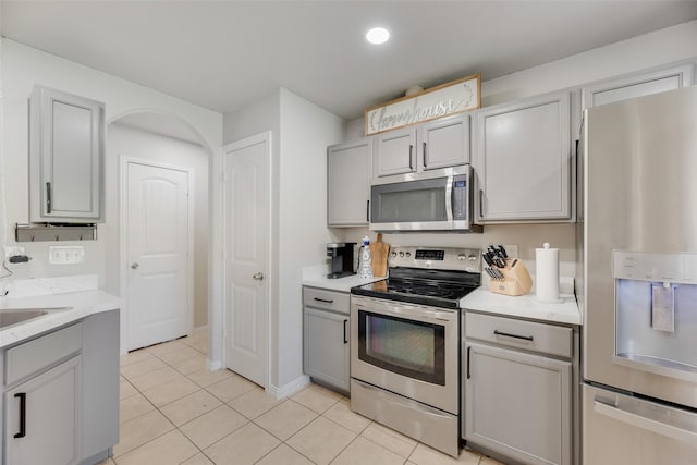5414 Wild Oak Rd, Balch Springs, TX 75180 - kitchen with appliances with stainless steel finishes, gray cabinetry, light tile patterned floors, a sink, and baseboards