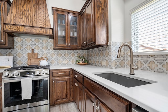 1208 Claire St, Lantana, TX 76226 - kitchen with stainless steel gas range oven, custom exhaust hood, light countertops, tasteful backsplash, and glass insert cabinets