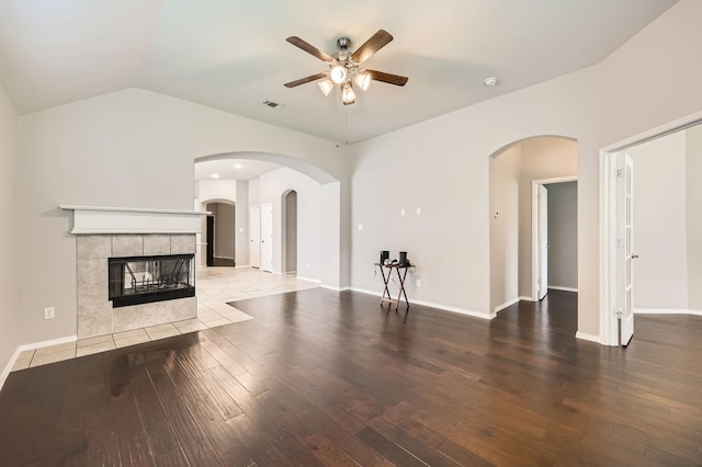 2124 Leonard Ranch Rd, Fort Worth, TX 76134 - unfurnished living room featuring a ceiling fan, a tile fireplace, wood finished floors, lofted ceiling, and arched walkways