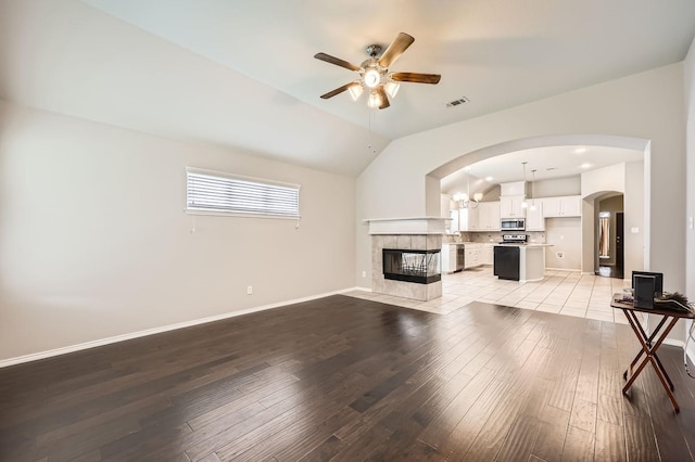 2124 Leonard Ranch Rd, Fort Worth, TX 76134 - unfurnished living room with ceiling fan, light wood-type flooring, arched walkways, lofted ceiling, and a tile fireplace