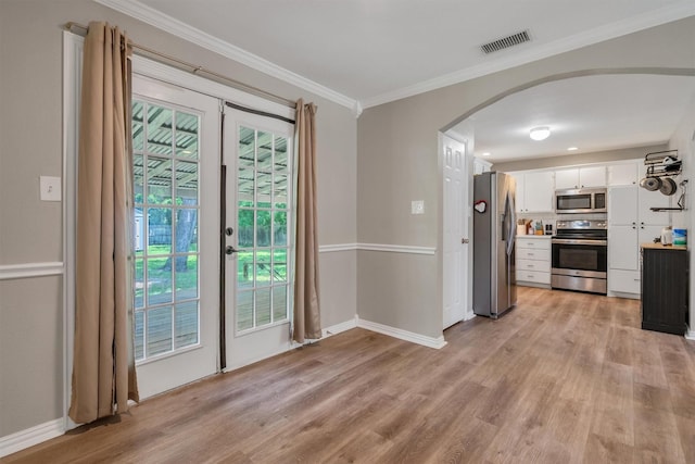 203 Olive St, Waxahachie, TX 75165 - kitchen with stainless steel appliances, arched walkways, crown molding, white cabinets, and light wood-style floors